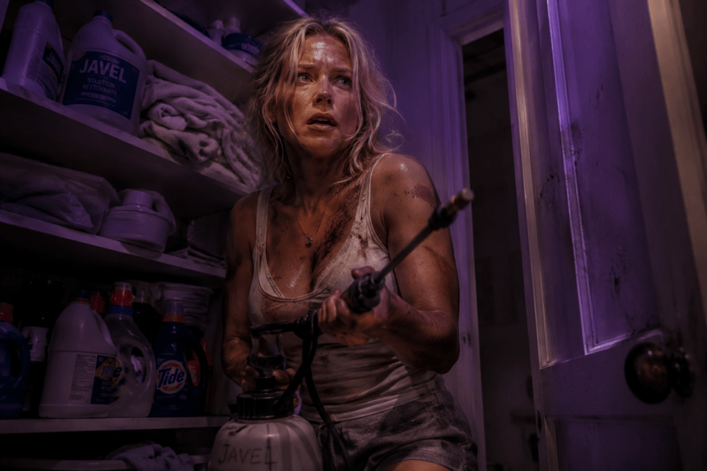 Jenny holding a manual pressure sprayer in a dimly lit, purple-toned supply closet, looking nervous and covered in dirt.